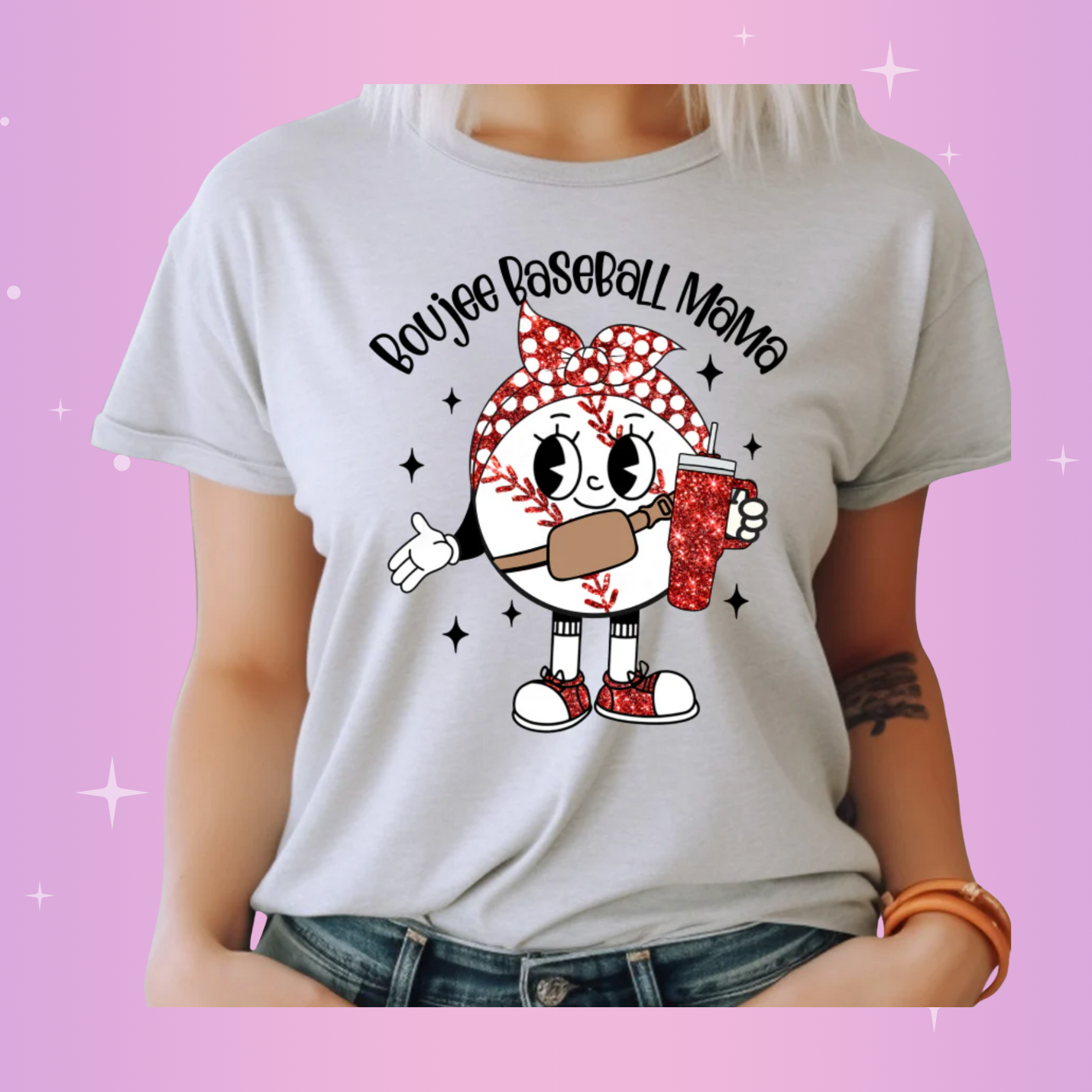 A woman wearing a white crew neck t-shirt with a graphic that includes text 'Baseball Mom' and depicts an illustrated character with a baseball and accessories.