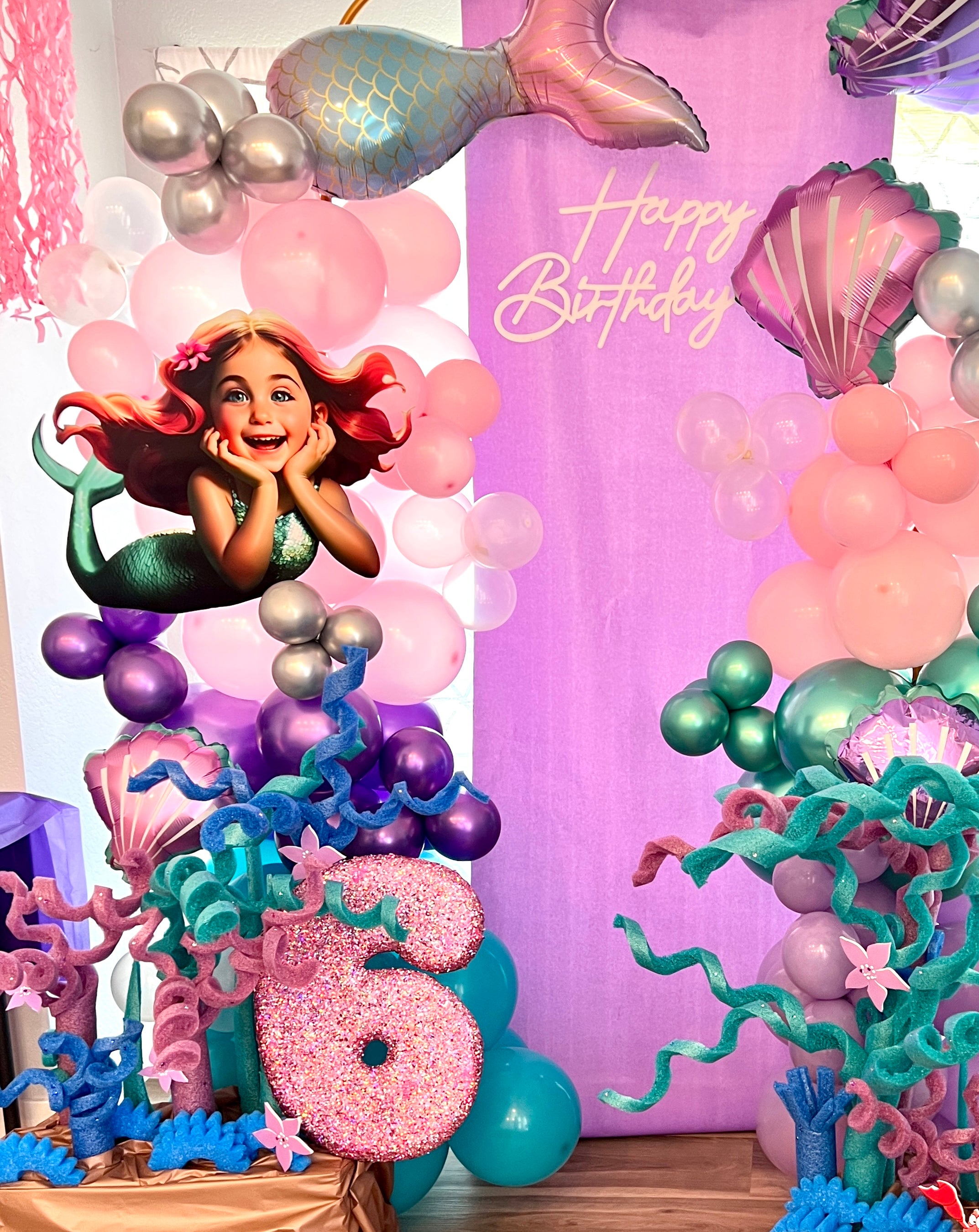 Mermaid-themed birthday party setup with balloons and decorations.
