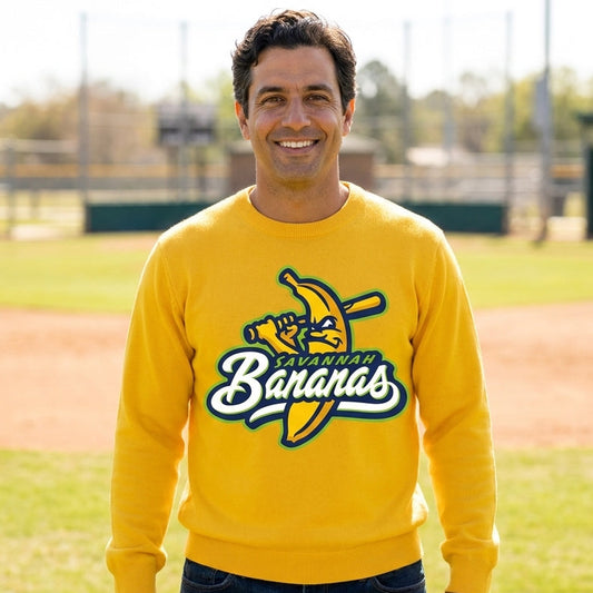 a sports dad on a baseball field wearing a yellow crew neck sweater with an illustration logo